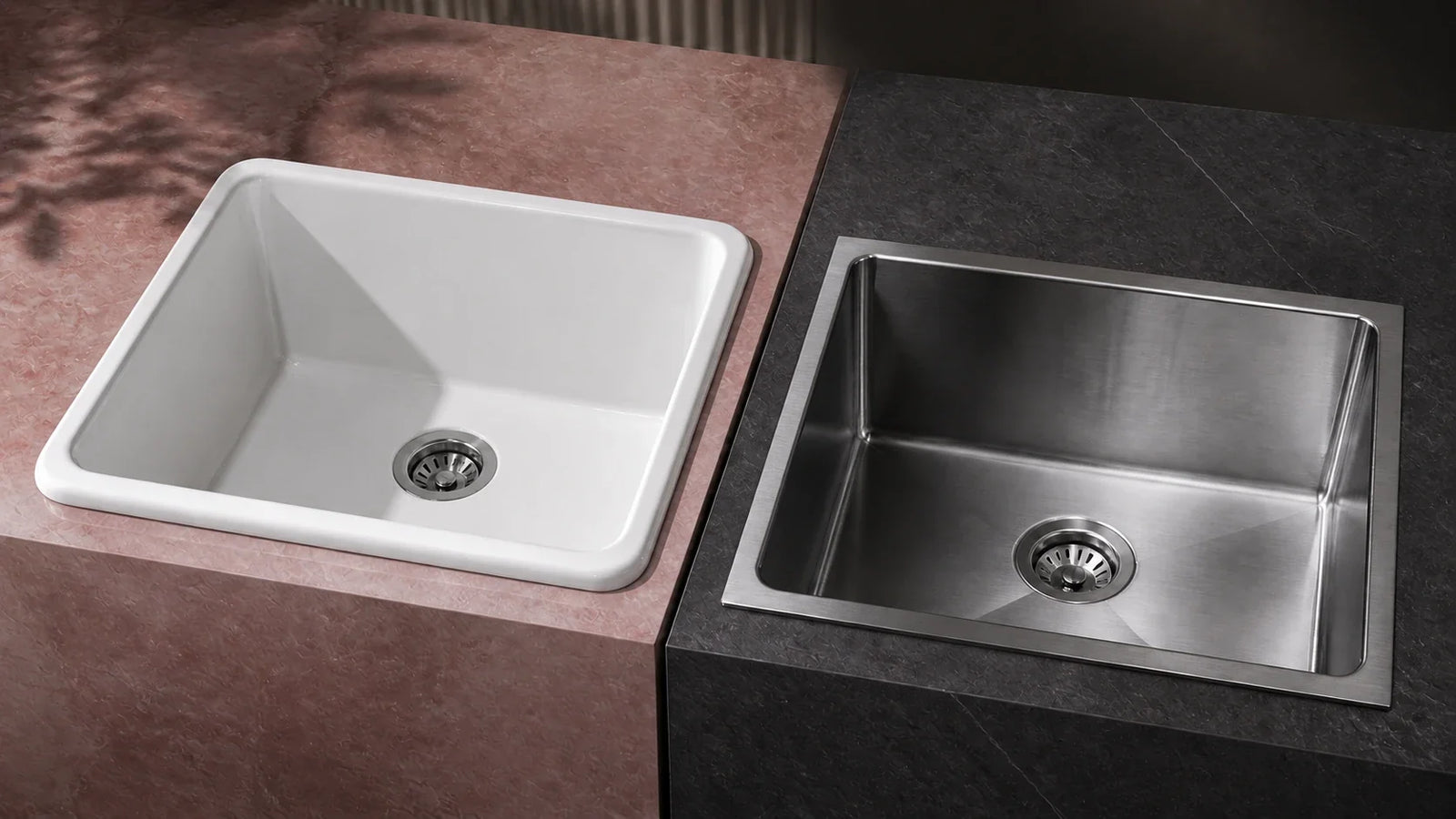 A glossy white sink beside a brushed stainless steel sink on contrasting stone counters