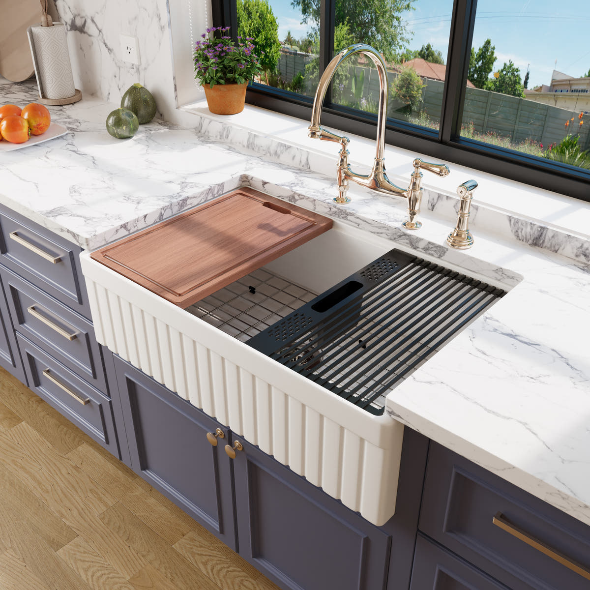 White 33 inch fluted fireclay farmhouse workstation sink with cutting board and roll-up drying rack in a blue kitchen with marble countertops