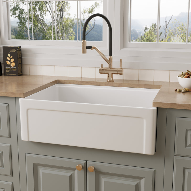 NOZLOO 30 inch grooved apron fireclay farmhouse sink with recessed panel front, installed in a sage green kitchen with butcher block countertop