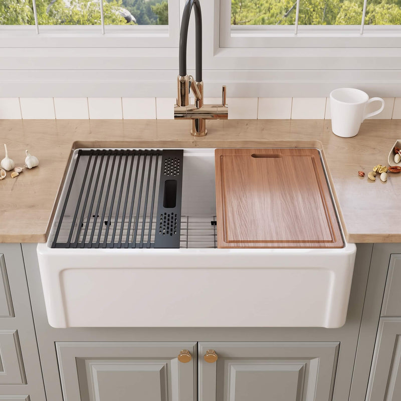 30 inch Grooved Apron Fireclay Farmhouse Sink with Workstation Kit featuring a cutting board, roll-up drying rack, bottom grid, and black colander tray on the integrated ledge