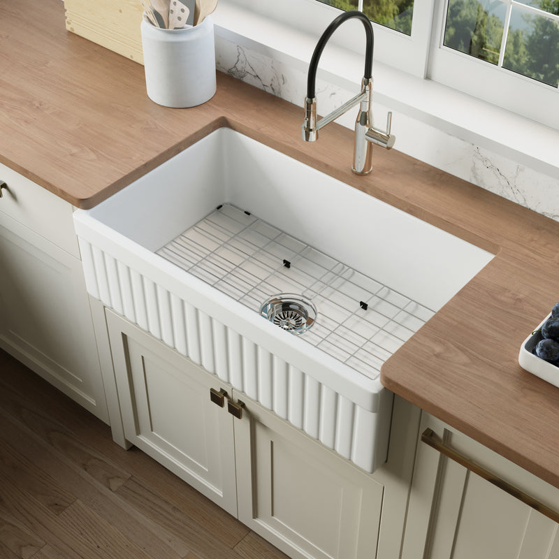 NOZLOO 33 inch reversible fluted apron fireclay farmhouse sink with bottom grid in a cream kitchen