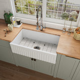 NOZLOO 33 inch reversible fluted apron fireclay farmhouse sink with bottom grid, top view in a sage green kitchen