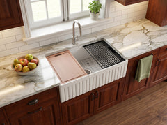 33 inch ribbed apron fireclay farmhouse sink installed in kitchen with cutting board and roll-up drying rack