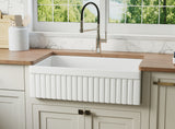 Reversible apron fireclay farmhouse sink with fluted front in bright kitchen