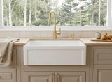 30 inch grooved fireclay farmhouse sink styled under a brass faucet in a bright kitchen