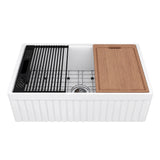 NOZLOO 30-inch fluted apron fireclay farmhouse workstation sink with sapele cutting board, roll-up drying rack, black colander, and stainless steel bottom grid on a white background