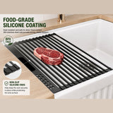 Black silicone-coated roll-up rack over a white fireclay sink, holding a steak with BPA-free, non-slip ends.