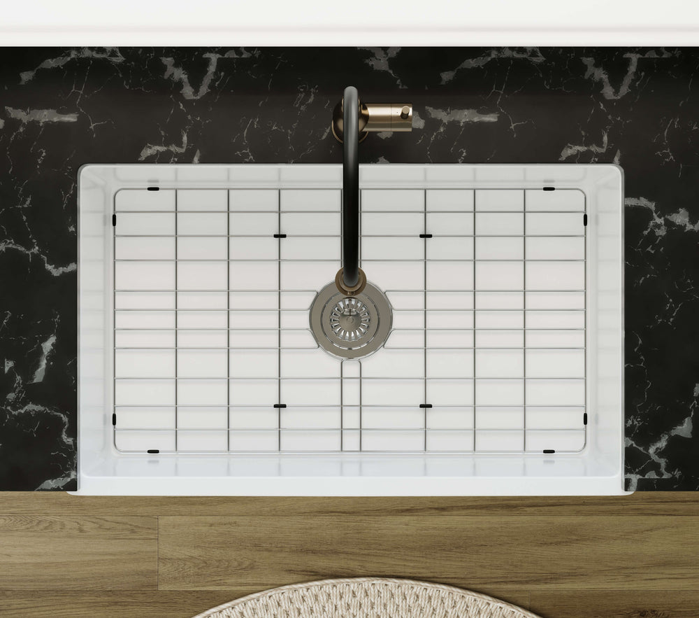 Top-down view of the NOZLOO NZ-3320T fireclay farmhouse sink installed in a black stone countertop with its fitted stainless steel bottom grid and drain.